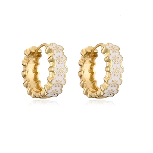 Close-up of gold-plated hoop earrings with white enamel and delicate floral pattern