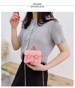 Pink jelly mini messenger bag with gold chain strap and magnetic snap closure on a bench