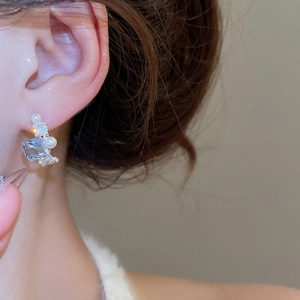 Detail of silver drop earring featuring a light blue crystal and elegant pearl on a model