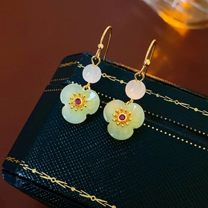 Detailed view of gold-plated flower earrings with green petals and red zircon inlay