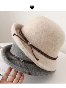 Detail of wool cloche hats with leather cord and silver heart charms in cream and grey