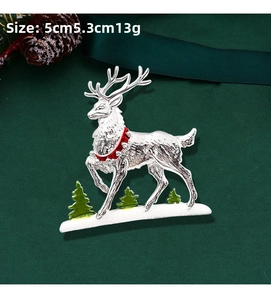 Detailed Christmas reindeer brooch with red enamel and pine trees in festive setting