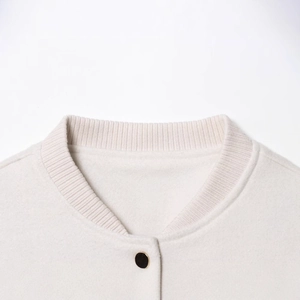 Close-up of cream baseball jacket with ribbed round neck and gold-trimmed button detail