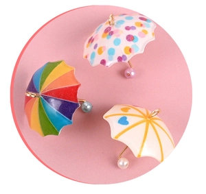 Close-up of three colorful dollhouse umbrella pendants with pearls for DIY jewelry making