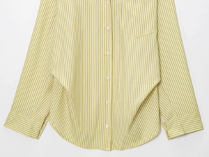 Detail of yellow and white vertical stripes on smooth poplin shirt with curved hem