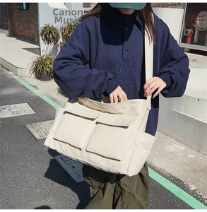 Detail view of large cream canvas messenger bag with double front flap pockets