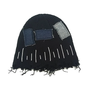 Schwarze Strickmütze mit ausgefransten Rändern und dekorativen Denim-Patchwork-Details