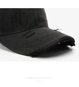 Close-up of distressed details and worn-out edges on a black vintage cotton baseball cap