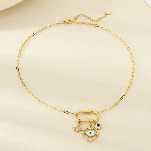 Detail of gold star and moon evil eye charms on long-link chain necklace with clasp