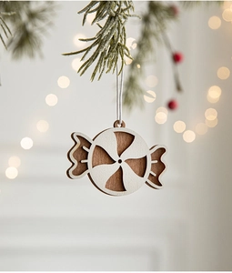 Close-up of candy-shaped wooden Christmas ornament with white paint and natural wood grain