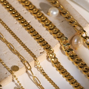 Detailed macro shot of 18K gold-plated stainless steel Cuban chains and pearl charms