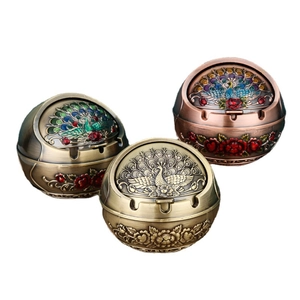 Three spherical peacock ashtrays in bronze and enamel finish with lids on white background