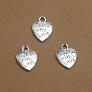 Vista macro de colgantes corazón Made with Love en plata vintage para joyería artesanal