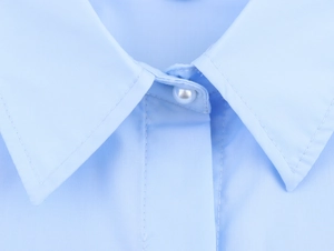Detail eines hellblauen Popeline-Hemdkragens mit glänzendem Perlenknopf-Verschluss
