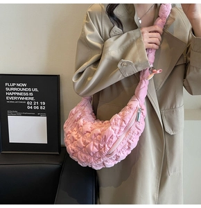 Detailed close-up of a pink quilted cloud bag with plush pleated texture and zip closure