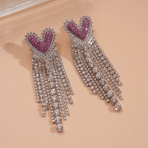 Gros plan détaillé de boucles d'oreilles cœur en strass rose avec pompons argentés