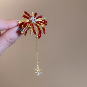 Detail of red enamel oval earring with gold metalwork and sparkling star dangle charm