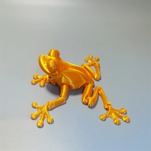 Macro detail of 3D printed orange frog model showing clear manufacturing layer textures