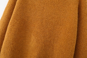 Detailed close-up of ginger yellow knit sweater showing vertical ribbed texture and soft wool