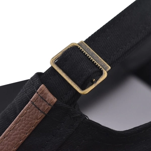 Detail of adjustable metal buckle and leather strap on a black cotton flat top army cap