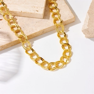 Polished gold double-link chain necklace with textured finish on beige stone