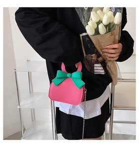 Close-up of a pink mini crossbody bag with cute bow detail and metal chain strap