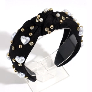 Close-up of knot headband with faux pearls and rhinestones on black textured fabric