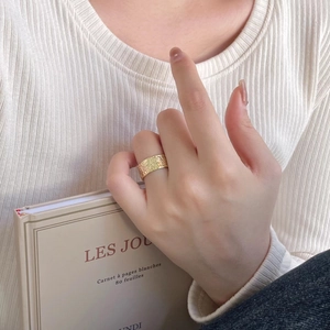 Close-up of golden wide hammer textured ring on a hand over a vintage French book