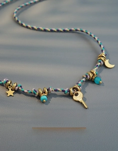 Detailed view of handmade woven necklace with gold moon key charms and turquoise beads