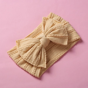 Close-up detail of a soft yellow cable-knit baby headband with a large bow design