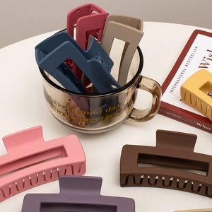 Detail of matte square hair claws in various colors arranged on a white table and glass