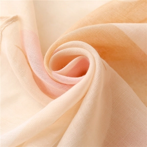 Macro shot of breathable cotton linen scarf with soft pink and orange gradient texture