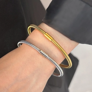 Detailed view of snake-bone textured metal bangle in gold and silver finishes