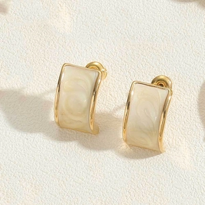 Detailed macro view of heart-shaped cream pearl earrings with gold-plated metal borders