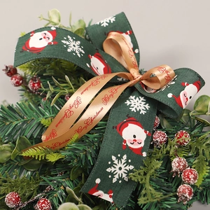 Fiocco natalizio con nastro di Babbo Natale e testo augurale su fogliame artificiale