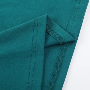 Vue macro de l'ourlet à double couture sur une robe longue vert foncé en maille