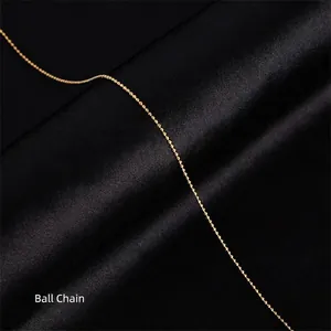 Macro shot of an 18k gold-plated bead chain necklace on a black silk background