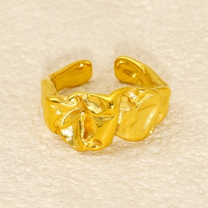 Dettaglio ravvicinato di un anello aperto dorato 18k con texture irregolare e design artistico