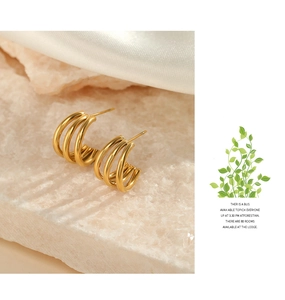 Close-up of gold-plated triple-layer C-shaped hoop earrings on elegant stone base