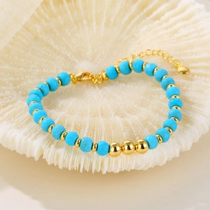 Bohemian beaded bracelet with turquoise stones and gold metal beads on coral background