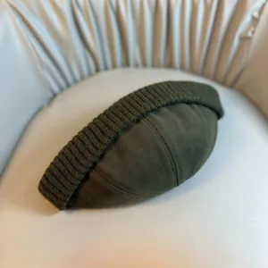 Detail view of deep olive green Docker cap with rib-knit brim and twill canvas crown