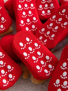 Macro view of red festive baby socks featuring white anti-slip silicone paw prints on soles