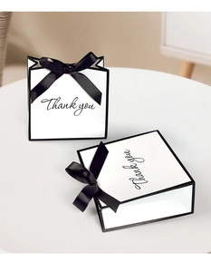 Detail of white gift bag with black bow and 'Thank you' cursive text for events