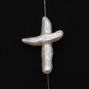 Macro shot of cross-shaped baroque freshwater pearl with natural iridescent white luster