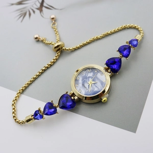 Detail of gold heart charm watch featuring blue marble dial and sparkling gemstones