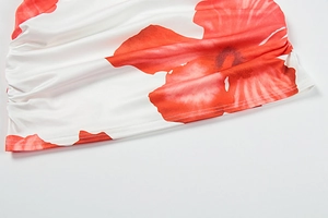 Close-up of side ruching detail on white skirt with red floral patterns and elastic fabric