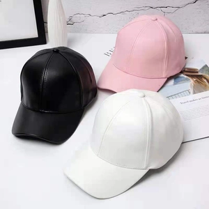 Solid candy-colored PU leather baseball caps in black, pink, and white on a clean desk