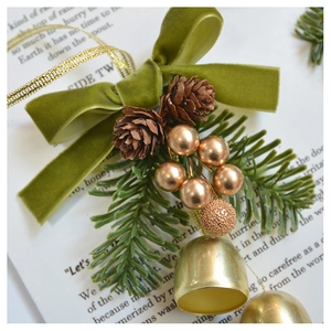 Close-up of olive green velvet bow with pine cones and golden bells for Christmas décor