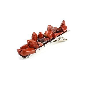 Detailed side view of silver hair clip with raw red crystal stones on white background