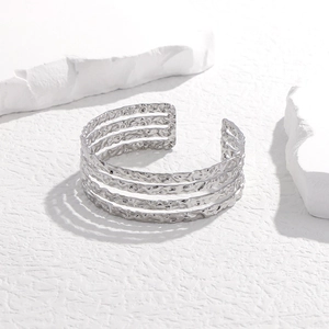 Macro detail of silver titanium steel bangle with irregular hammered texture and hollow layers